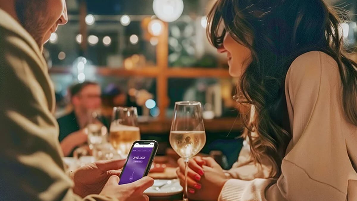 Young couple having dinner in a restaurant. The man ist holding a phone with the we-vibe app